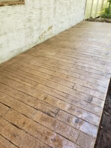 A textured concrete patio designed to resemble wooden planks is adjacent to a white stucco wall.